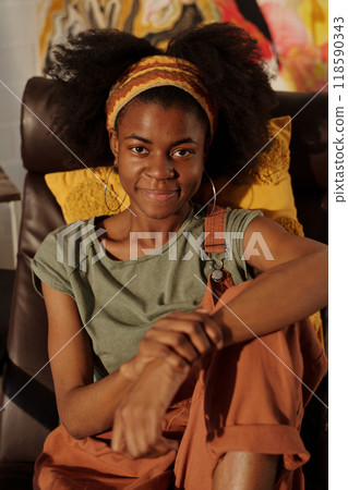 Relaxing and Smiling Young Woman Sitting on Sofa at Home 118590343
