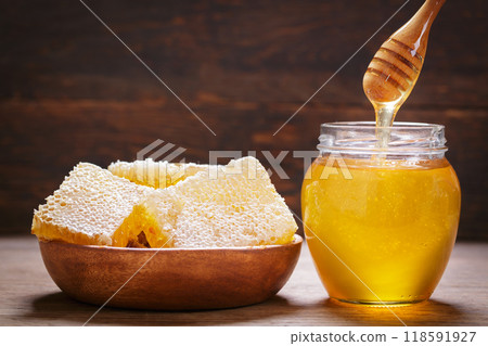 Fresh honey drips into jar of honey 118591927