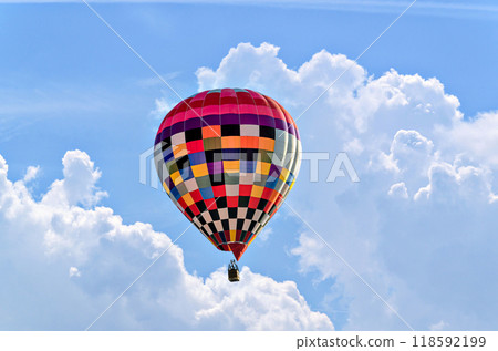 Colorful hot air balloon flying over blue sky with white clouds Colorful hot air balloon flying over blue sky with white clouds 118592199