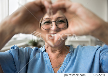 Woman wear glasses showing heart symbol to camera Woman wear glasses showing heart symbol to camera 118592291