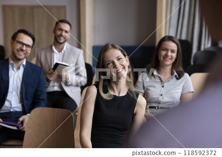 Happy cheerful young businesswoman attending conference, sitting in first line Happy cheerful young businesswoman attending conference, sitting in first line 118592372