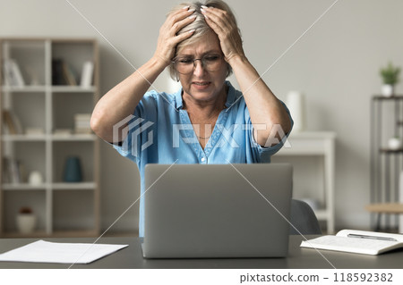 Senior woman experiencing stress while using her laptop Senior woman experiencing stress while using her laptop 118592382