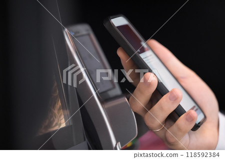 Male hand holding smartphone at POS terminal device Male hand holding smartphone at POS terminal device 118592384