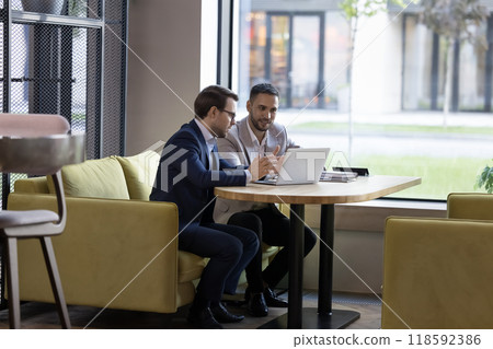 Two engaged business partners talking at laptop in office cafe 118592386