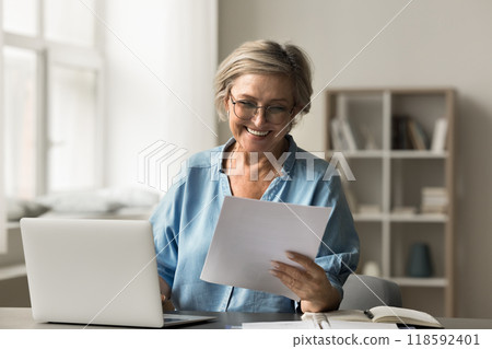 Happy smiling mature woman reading a document 118592401