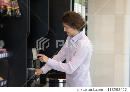 Positive young consumer man buying coffee at vendor shop Positive young consumer man buying coffee at vendor shop 118592422
