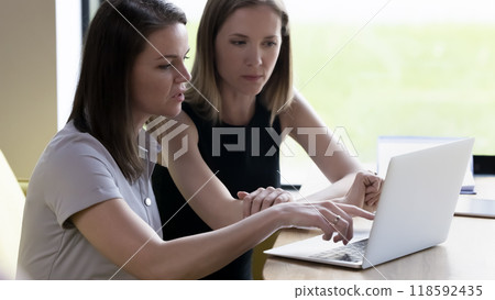 Two serious business colleagues women watching online presentation Two serious business colleagues women watching online presentation 118592435
