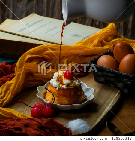 將大量焦糖醬倒入鋪有鮮奶油和櫻桃的布丁中的那一刻。 將大量焦糖醬倒入鋪有鮮奶油和櫻桃的布丁中的那一刻。 118593318