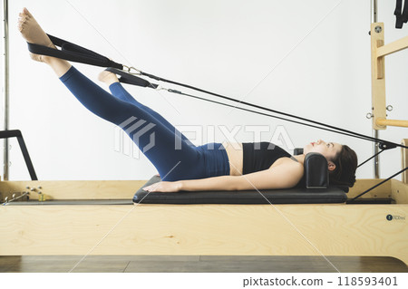 Young woman doing pilates using a machine Young woman doing pilates using a machine 118593401