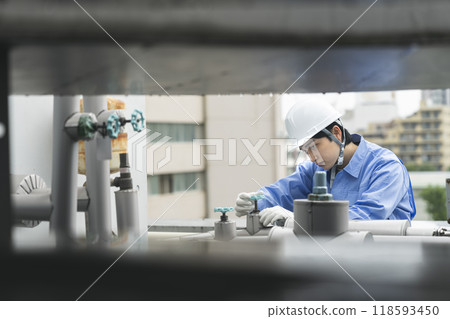 Workers inspecting the water supply and drainage equipment on the roof of a building. Building maintenance image. 118593450
