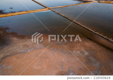 Aerial view of salt pans at sunset showcasing water and land contrast Aerial view of salt pans at sunset showcasing water and land contrast 118593629