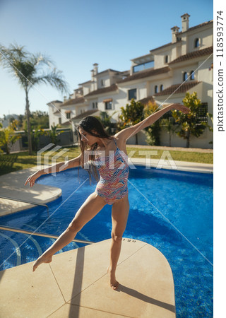 A Graceful Young Dancer at Poolside Embraced by Bright Sunshine and Vibrant Colors A Graceful Young Dancer at Poolside Embraced by Bright Sunshine and Vibrant Colors 118593774