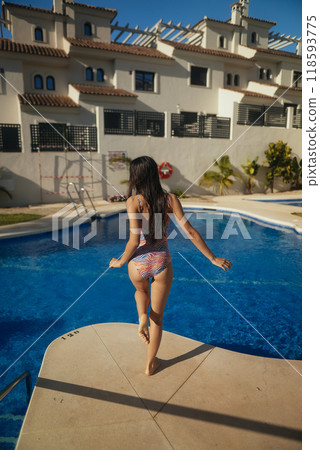 A happy woman joyfully walking by a beautiful pool in a blissful summer paradise setting A happy woman joyfully walking by a beautiful pool in a blissful summer paradise setting 118593775