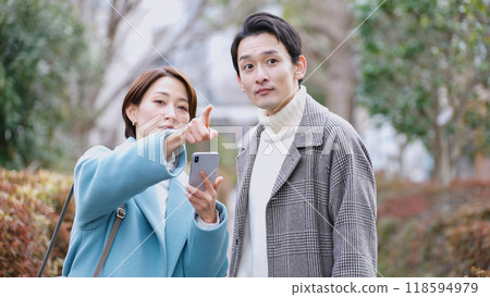 A couple looking at a smartphone (winter clothes, coat, jacket) 118594979