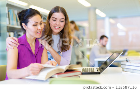 Two female friends studying together at library Two female friends studying together at library 118597116