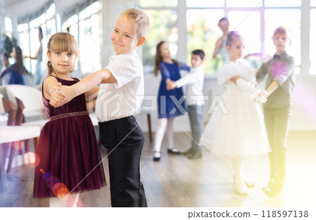 Positive little boys and girls in festive clothes dancing pair dance in ballet studio Positive little boys and girls in festive clothes dancing pair dance in ballet studio 118597138
