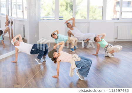 Happy girl and teens doing breakdance in dance hall with male trainer in choreography studio Happy girl and teens doing breakdance in dance hall with male trainer in choreography studio 118597483