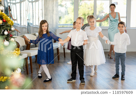 Little children standing in pairs in school-hall decorated with Xmas tree 118597609