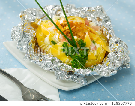 Cooked baked potatoes in foil with filling of bacon, fried onion and cheese 118597776