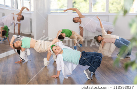 Dynamic happy boy training breakdance drops during workout session with group of children in studio Dynamic happy boy training breakdance drops during workout session with group of children in studio 118598027