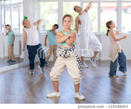 Positive cheerful smiling children studying modern style dance in class indoors with male teacher 118598043