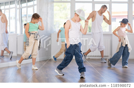 Happy emotional male teenager rehearsing popping techniques during group workout in modern street dance studio 118598072
