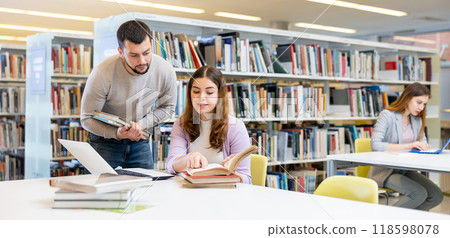 Man working with female colleague on joint project in library 118598078
