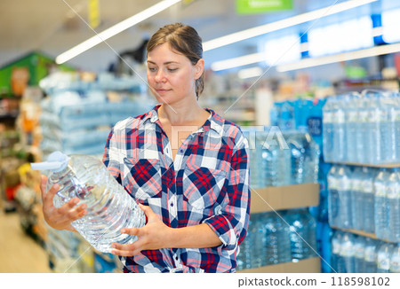 Portrait of attractive woman choosing water in bottle at supermarket 118598102
