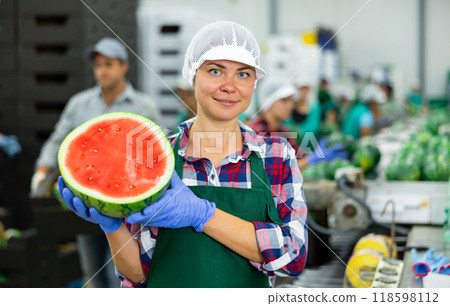 Female agricultural facility worker holding half of fresh watermelon Female agricultural facility worker holding half of fresh watermelon 118598112