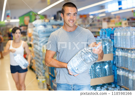 Portrait of adult man choosing water in bottle at supermarket Portrait of adult man choosing water in bottle at supermarket 118598166
