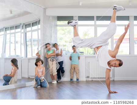 Young breakdancer demonstrating dance moves to group of tweens in studio 118598268