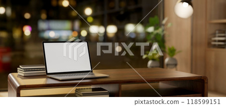 A laptop sits on a hardwood coffee table by a window with a night city view in a cozy living room. A laptop sits on a hardwood coffee table by a window with a night city view in a cozy living room. 118599151