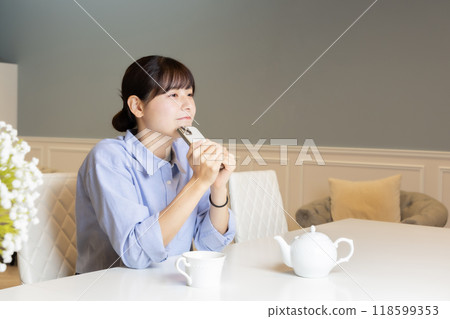 A woman who manipulates a smartphone in the living room A woman who manipulates a smartphone in the living room 118599353