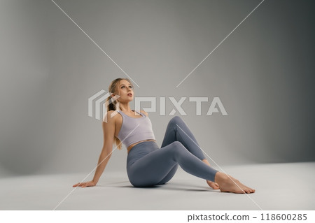 Young woman in activewear practicing yoga in a studio with neutral backdrop Young woman in activewear practicing yoga in a studio with neutral backdrop 118600285