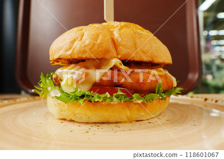 A mouthwatering cheeseburger stacked high with fresh toppings, nestled on a rustic plate ready to be enjoyed in a cozy setting A mouthwatering cheeseburger stacked high with fresh toppings, nestled on a rustic plate ready to be enjoyed in a cozy setting 118601067