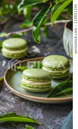 Matcha Green Tea Macarons: Green tea macarons with white chocolate ganache on a ceramic plate with tea leaves 118601334