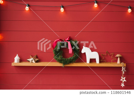 Red wall with a shelf and decorations include a christmas wreath, horse, and star 118601546