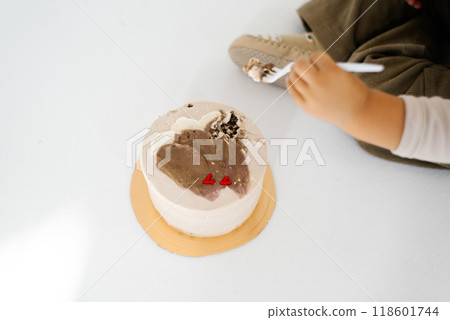 Child is eating a cake with a red heart on it. Hands top view 118601744
