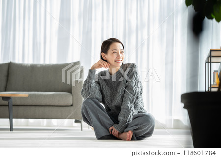 Woman relaxing in living room window 118601784