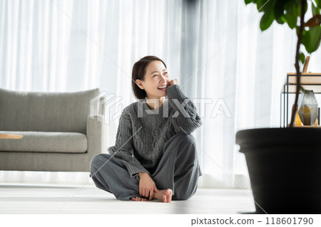 Woman relaxing in living room window Woman relaxing in living room window 118601790