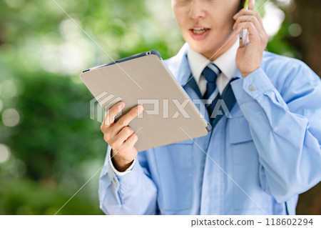 穿著工作服的男人拿著平板電腦和智慧型手機 穿著工作服的男人拿著平板電腦和智慧型手機 118602294