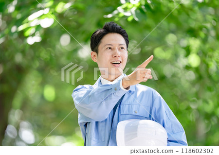 Man in work clothes pointing and checking Man in work clothes pointing and checking 118602302