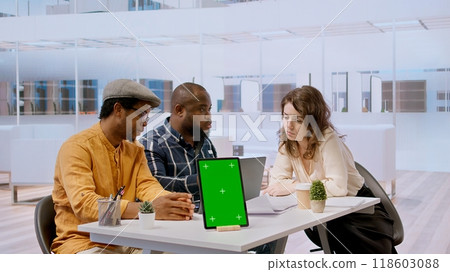Businessman discussing with the real estate agents next to chroma key on tablet, meeting to negotiate leasing contract terms before looking at blueprints for an office relocation. Camera A. 118603088