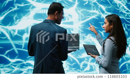 Programmers using devices and AI neural networks modeled after human brain to solve complex problems. Workers using artificial intelligence deep learning to look at data and complete tasks, camera A 118603103