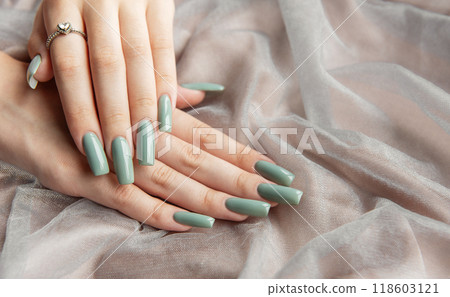 Elegant hands with long green nails resting on soft fabric Elegant hands with long green nails resting on soft fabric 118603121