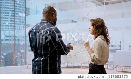 Business managers meeting with a realtor for a real estate office tour, planning an investment with detailed blueprints and architectural design. Examining layout sketches. Camera A. Business managers meeting with a realtor for a real estate office tour, planning an investment with detailed blueprints and architectural design. Examining layout sketches. Camera A. 118603273