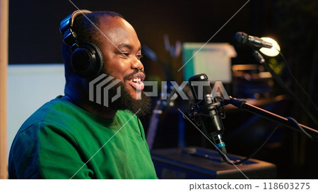 Young songwriter playing piano and singing on microphone, recording his new music and mixing the tunes on digital software. Musician composer producing soundtracks with modern gear. Camera A. 118603275