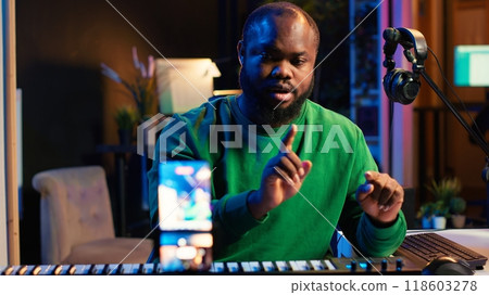 Musician doing online paid classes to help people play piano notes, teaching lessons from his home studio and recording video tutorials. Musical instructor playing midi controller keyboard. Camera A. Musician doing online paid classes to help people play piano notes, teaching lessons from his home studio and recording video tutorials. Musical instructor playing midi controller keyboard. Camera A. 118603278