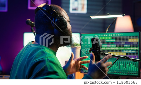 Artist producer singing a new song to record on microphone, preparing to edit music in post production. Musician expert applying mixing and mastering techniques on his audio recorded files. Camera A. Artist producer singing a new song to record on microphone, preparing to edit music in post production. Musician expert applying mixing and mastering techniques on his audio recorded files. Camera A. 118603565