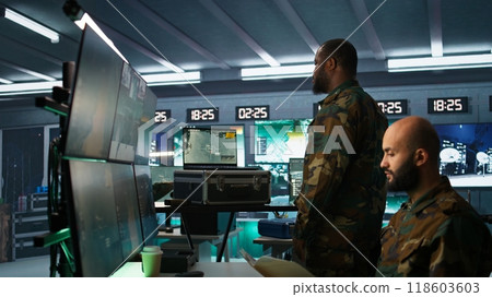 Military soldier wearing camo uniform in mission control center, overseeing national safety operations using laptop. Army expert examining data in monitoring room command center, camera B Military soldier wearing camo uniform in mission control center, overseeing national safety operations using laptop. Army expert examining data in monitoring room command center, camera B 118603603